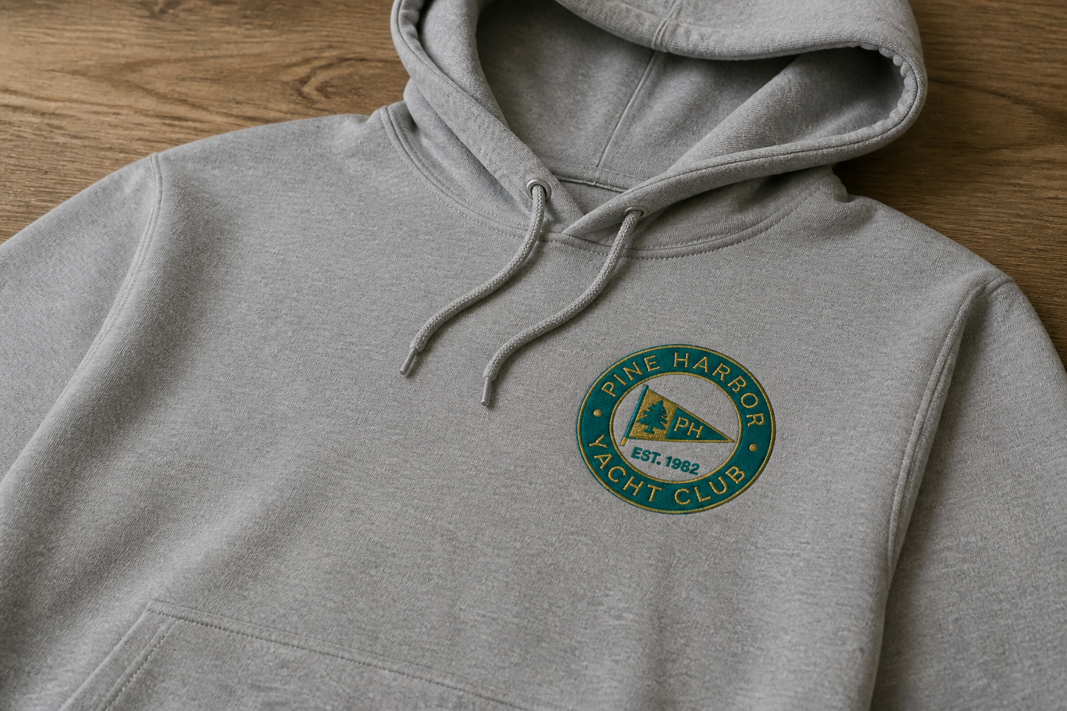 Machine-embroidered club logo on a gray hoodie