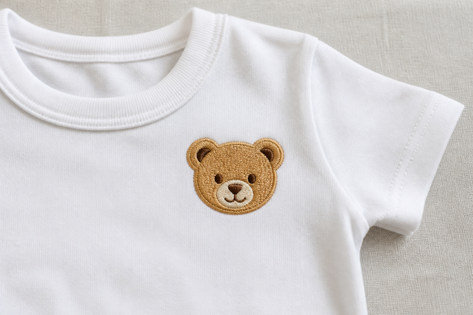 Small machine-embroidered teddy bear on a baby onesie